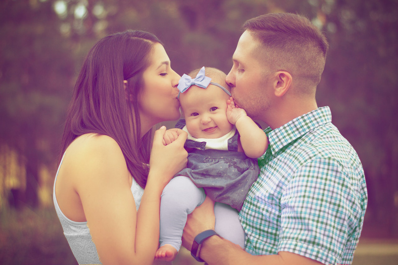 Mother and Father Kissing Infant Baby